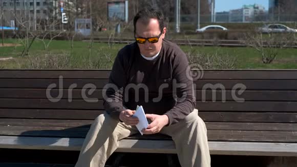 中年男子坐在户外清点现金视频的预览图
