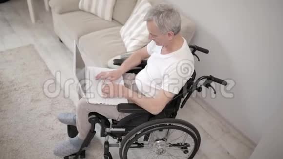 灰头土脸的男人坐在他的病房里的轮椅上坐在笔记本电脑前视频的预览图