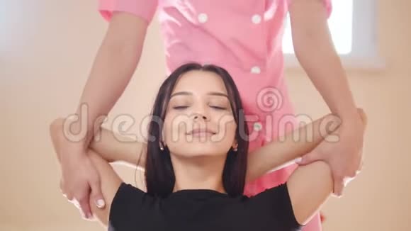 泰式按摩年轻的女人坐着享受另一个女人的肩膀按摩微笑视频的预览图