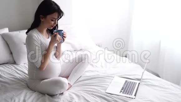 孕妇在卧室使用电脑喝茶视频的预览图