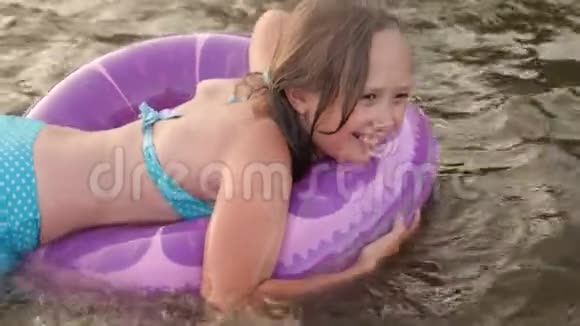 年轻漂亮的女孩正在一个充气圈的水里游泳女孩微笑着笑视频的预览图