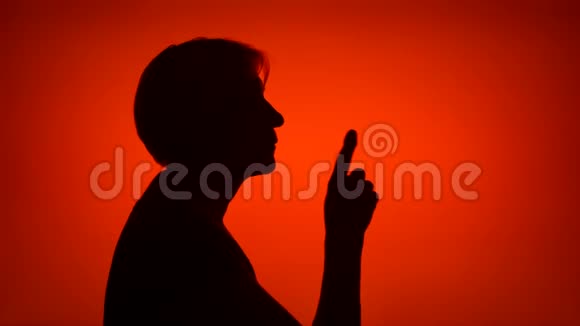 高级女性在红色背景下做沉默手势的剪影神秘和保密的概念视频的预览图