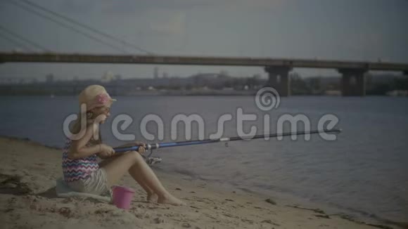 坐在河岸上拿着鱼竿的小女孩视频的预览图