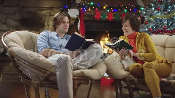 年轻的男人和成年的女人在圣诞节晚上看书讨论他们视频的预览图