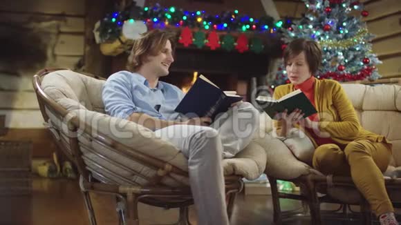 母亲和儿子在圣诞夜看书讨论他们笑着视频的预览图