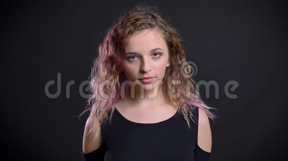 年轻女孩的画像粉红色的头发静静地看着镜头在黑色的背景视频的预览图