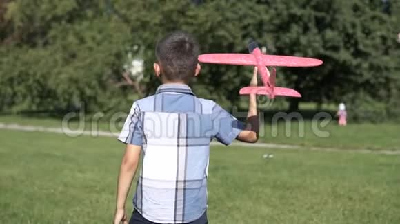 男孩在阳光明媚的天气在公园里开了一架玩具飞机慢动作高清高清视频的预览图