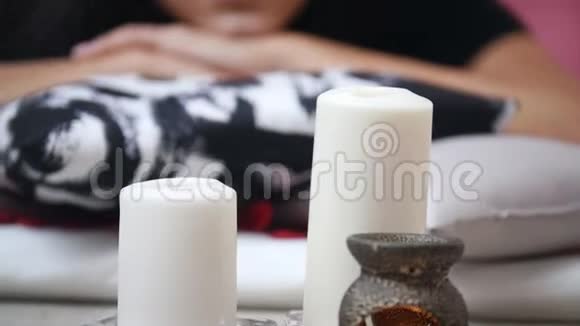泰式按摩年轻女子躺在垫子上接受头部按摩享受蜡烛视频的预览图