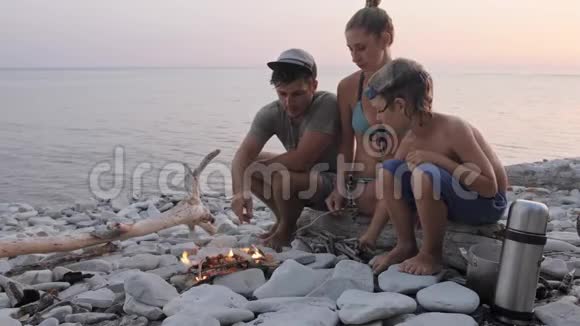 幸福的一家人在篝火旁的野生海滩上享受夏日日落视频的预览图