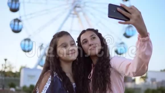 两个漂亮的女朋友在摩天轮的背景下自拍4K特写视频的预览图