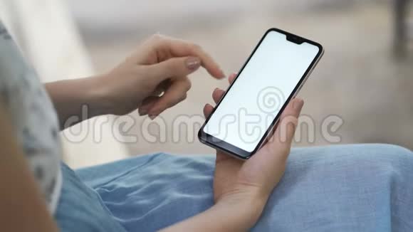 女性手拿白色屏幕的智能手机使用智能手机将智能手机与绿色屏幕放在时尚上视频的预览图