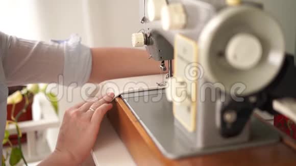 美丽的慢动作在家工作年轻的金发女人在明亮的房间里用打字机缝衣服视频的预览图