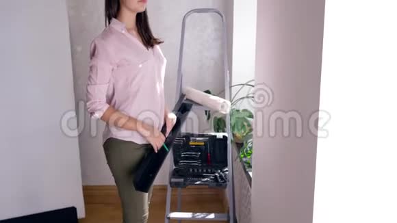 维修公寓可爱的女人在装修房子的时候重新装修把架子挂在墙上视频的预览图