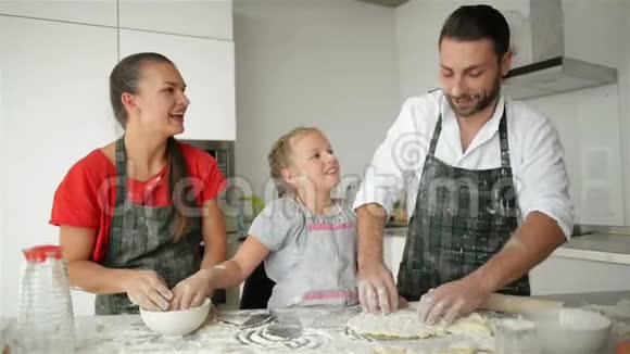 有白人外貌的父母在做饭的时候和他们的女儿在一起很开心看上去很有趣好心情视频的预览图