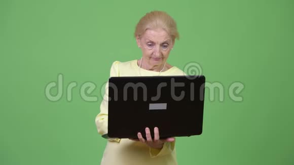 漂亮快乐的高级女商人用笔记本电脑思考视频的预览图
