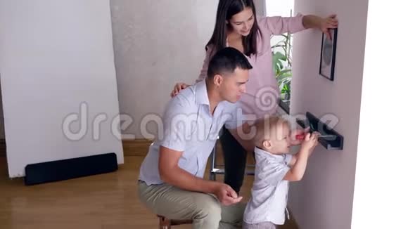 在公寓搬迁后可爱的孩子帮父母把架子栓到墙上视频的预览图