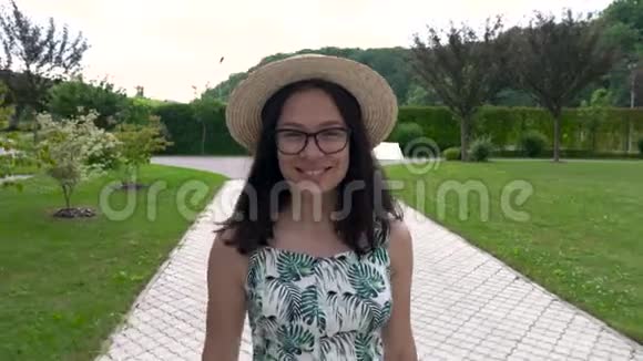 戴着帽子和夏装的亚洲女孩微笑着沿着公园的轨道走着享受生活视频的预览图