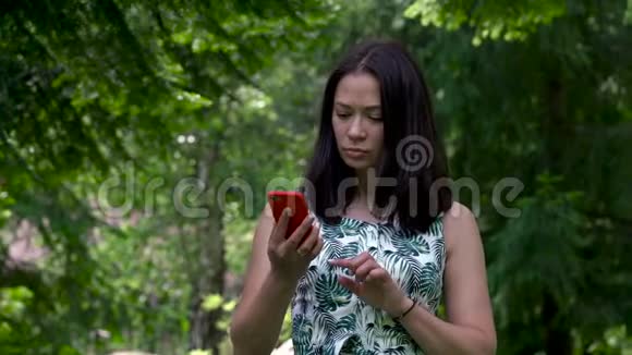 可爱的亚洲女孩试图连接到公园的蜂窝网络信号红色手机在她手里视频的预览图