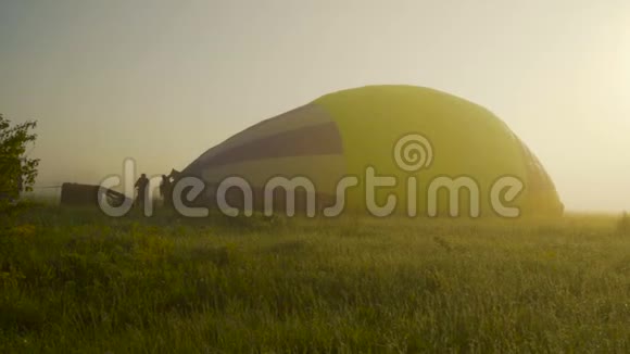 滑动摄像头充气热气球准备日落时的飞行雾草地上的露水背光视频的预览图