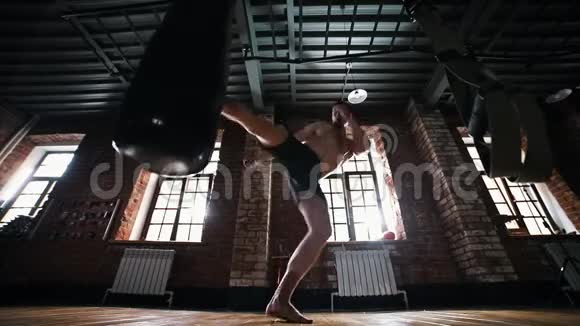 一个拳击手在健身房里踢拳击袋视频的预览图