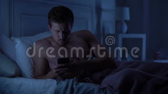 帅哥躺在床上在智能手机上保留令人失望的短信视频的预览图
