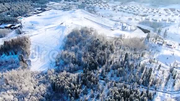 冬季在田野和森林中鸟瞰小村庄旅途冬天风景如画白雪覆盖视频的预览图