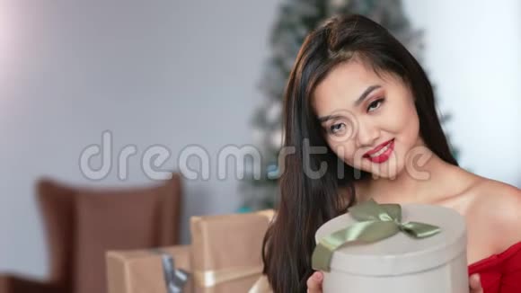 中等特写肖像迷人优雅的亚洲年轻女子手持礼品盒微笑视频的预览图