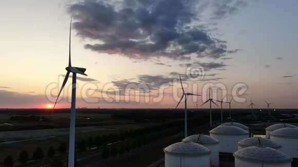 工业海港区有筒仓的一排风车在日落时发电视频的预览图