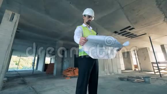 男工程师站在建筑工地的中间手里拿着蓝图视频的预览图