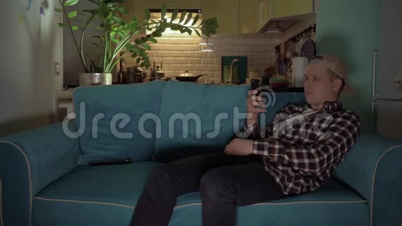 快乐的人躺在沙发上用手机玩游戏4K视频的预览图