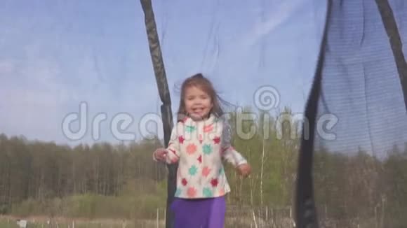 快乐的三岁女孩跳上蹦床情感愉悦的肖像慢动作视频的预览图