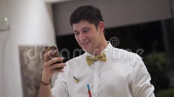 一个年轻人晚上在热带别墅的聚会上用手机拍摄照片和视频视频的预览图