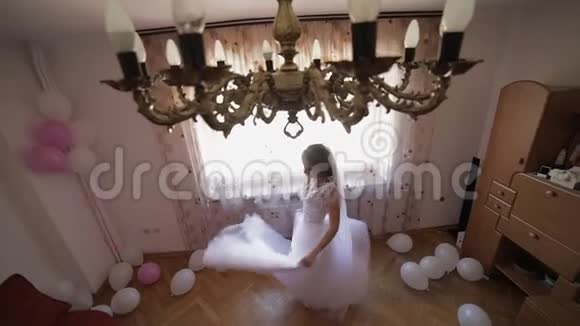 美丽可爱的新娘穿着婚纱在窗边跳舞结婚的早晨漂亮又整洁的女人慢动作视频的预览图