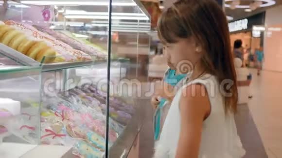 饥饿的男孩和女孩靠近一个玻璃橱窗有饼干和甜甜圈选择糖果视频的预览图