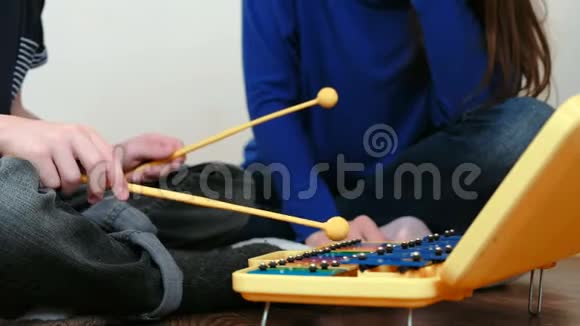 演奏音乐乐器特写男孩他的手在玩木琴他的妈妈坐在他身边视频的预览图