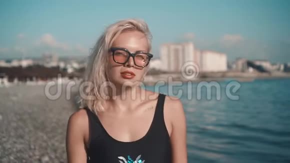 穿着泳衣的年轻性感女孩在海边散步金色的时髦太阳镜和一件泳衣视频的预览图