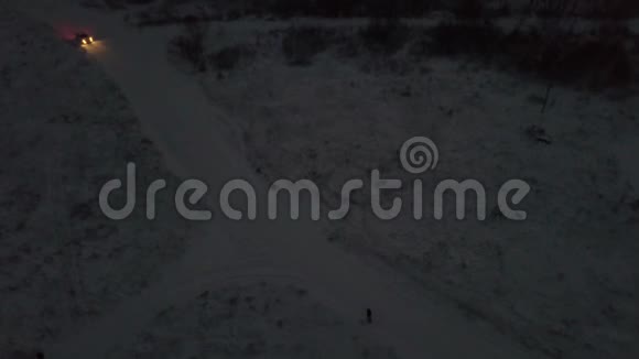 冬季人们在城外白色汽车附近被雪覆盖的道路上燃放烟花的鸟瞰图视频的预览图
