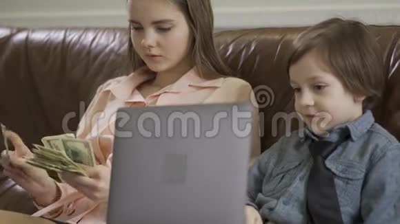 严肃的姐姐和弟弟坐在真皮沙发上那个拿着笔记本电脑的男孩那个正在数数的女孩视频的预览图