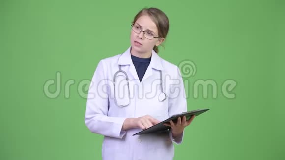 年轻漂亮的女医生一边看剪贴板一边解释视频的预览图