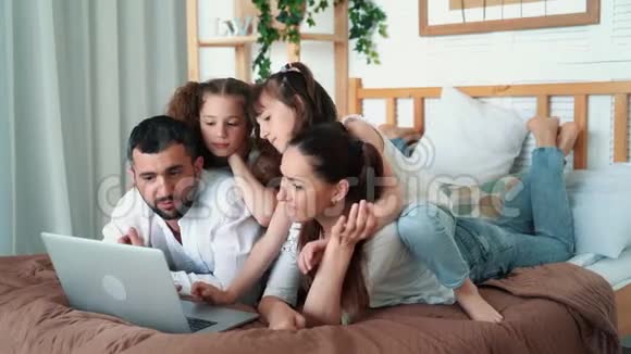 家庭幸福父母和两个女儿在笔记本电脑上看卡通慢动作视频的预览图