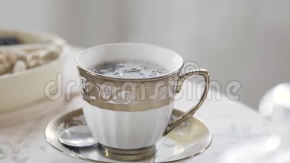 在光线充足的房间里用蒸汽把优雅的瓷杯热茶放在桌子上库存录像贵族视频的预览图