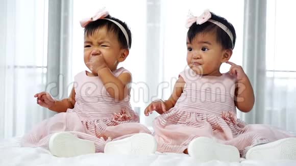两个穿着粉红色裙子的双胞胎宝宝躺在床上一个在看一个在哭视频的预览图