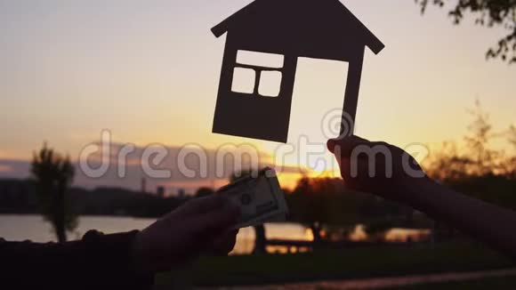 特写镜头的人们把钱放在微型房子的背景上视频的预览图