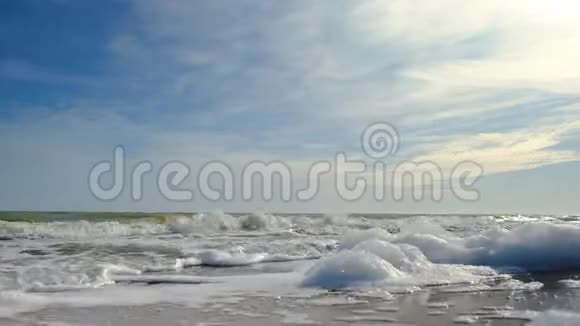 海水泡沫是在一个空旷的沙质冬季海滩上溅起的形成的靠近海泡视频的预览图