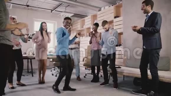 快乐的非裔美国员工与同事在办公室聚会上跳舞庆祝商业成就慢动作视频的预览图