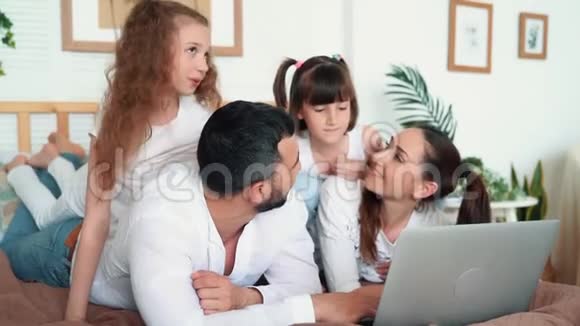 家庭幸福父母和两个女儿在笔记本电脑上看电影慢动作视频的预览图