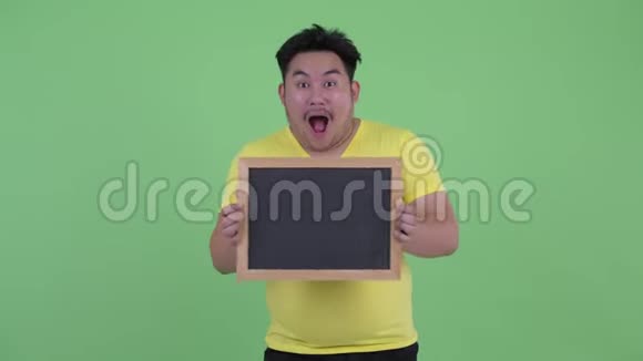 快乐年轻超重的亚洲人拿着黑板视频的预览图