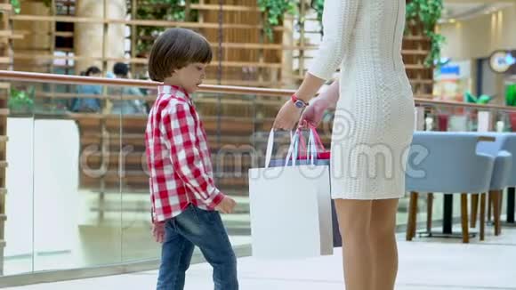 可爱的男孩和妈妈在商场里带着圣诞礼物家庭圣诞购物孩子和妈妈一起玩视频的预览图