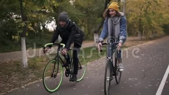 快乐的微笑的朋友或年轻的夫妇骑着自行车在秋天的公园骑自行车男子和妇女视频的预览图