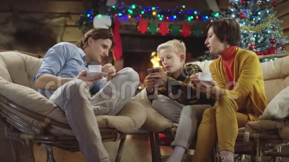 小男孩在圣诞夜给哥哥和妈妈看智能手机屏幕视频的预览图